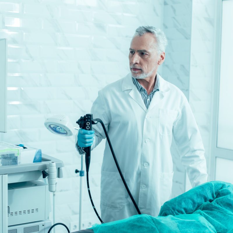doctor-maduro-serio-sosteniendo-endoscopio-moderno-preparandose-procedimiento